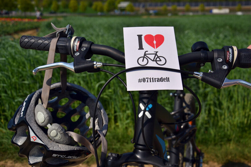 Blick auf einen Fahrradlenker an dem ein Helm hängt. Außerdem steckt eine Karte am Lenker mit Werbung für das Stadtradeln.